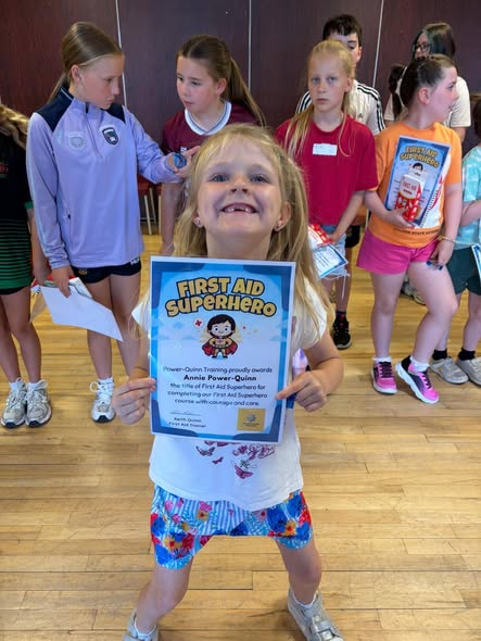 A First Aid Superheroes learner proudly holding a certificate