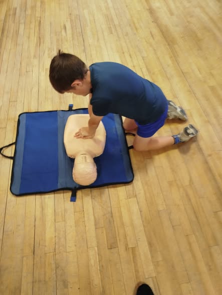 A young learner practising CPR on a first aid training manikin